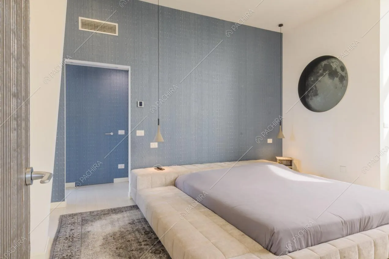 Letto matrimoniale nella luminosa camera con parete azzurra e bagno privato