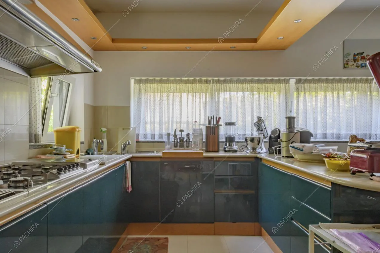Luminosa cucina blu petrolio, dalle pareti bianche e con piastrelle