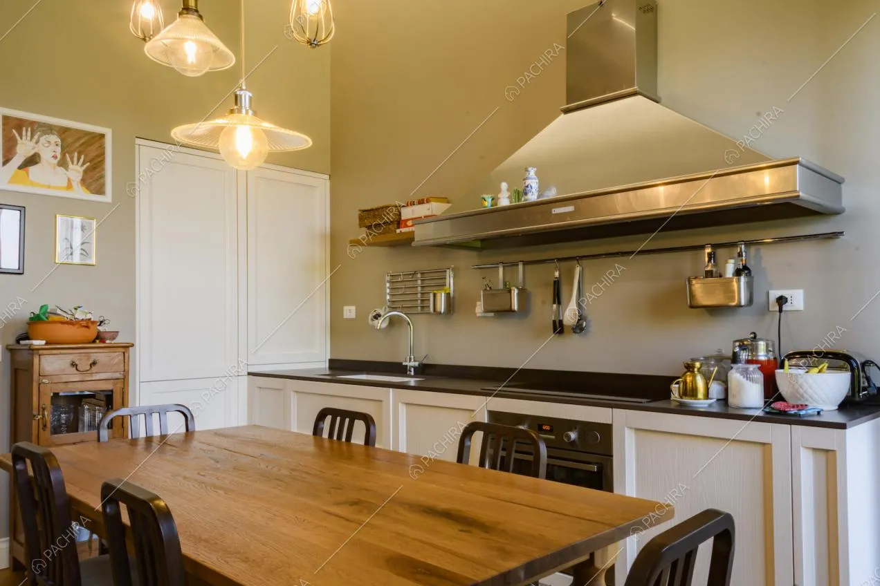 Cucina a parete bianca con grande cappa in alluminio e utensili
