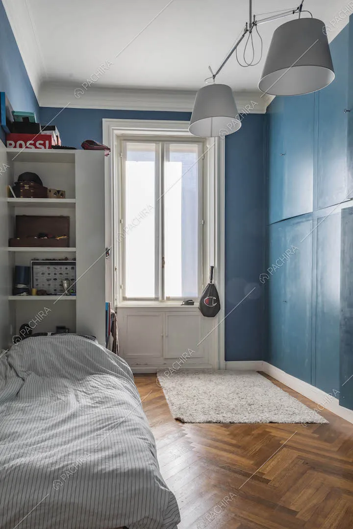 Camera da letto dalle pareti blu con armadio a parete e pavimento in parquet a spina di pesce