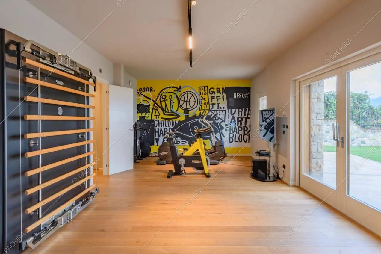 Palestra con pavimento in parquet, pareti bianche e porta-finestra per accedere alla terrazza