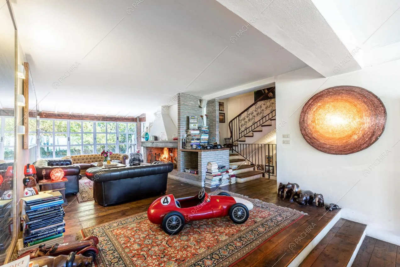 Sala con camino, pavimento in parquet, finestre in stile industriale e vista sulle scale