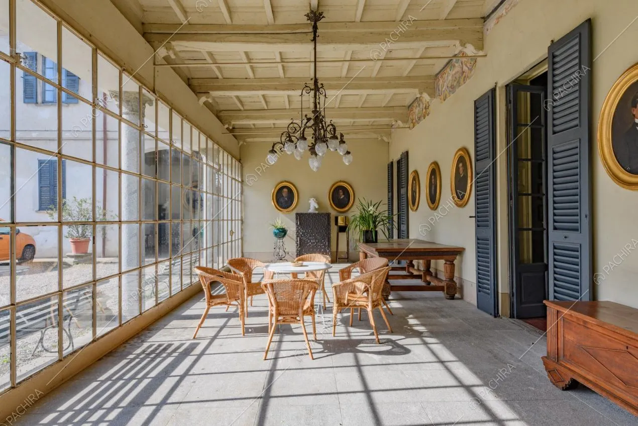 Luminosa veranda con soffitto in travi in legno a vista e tavolo con poltrone di vimini