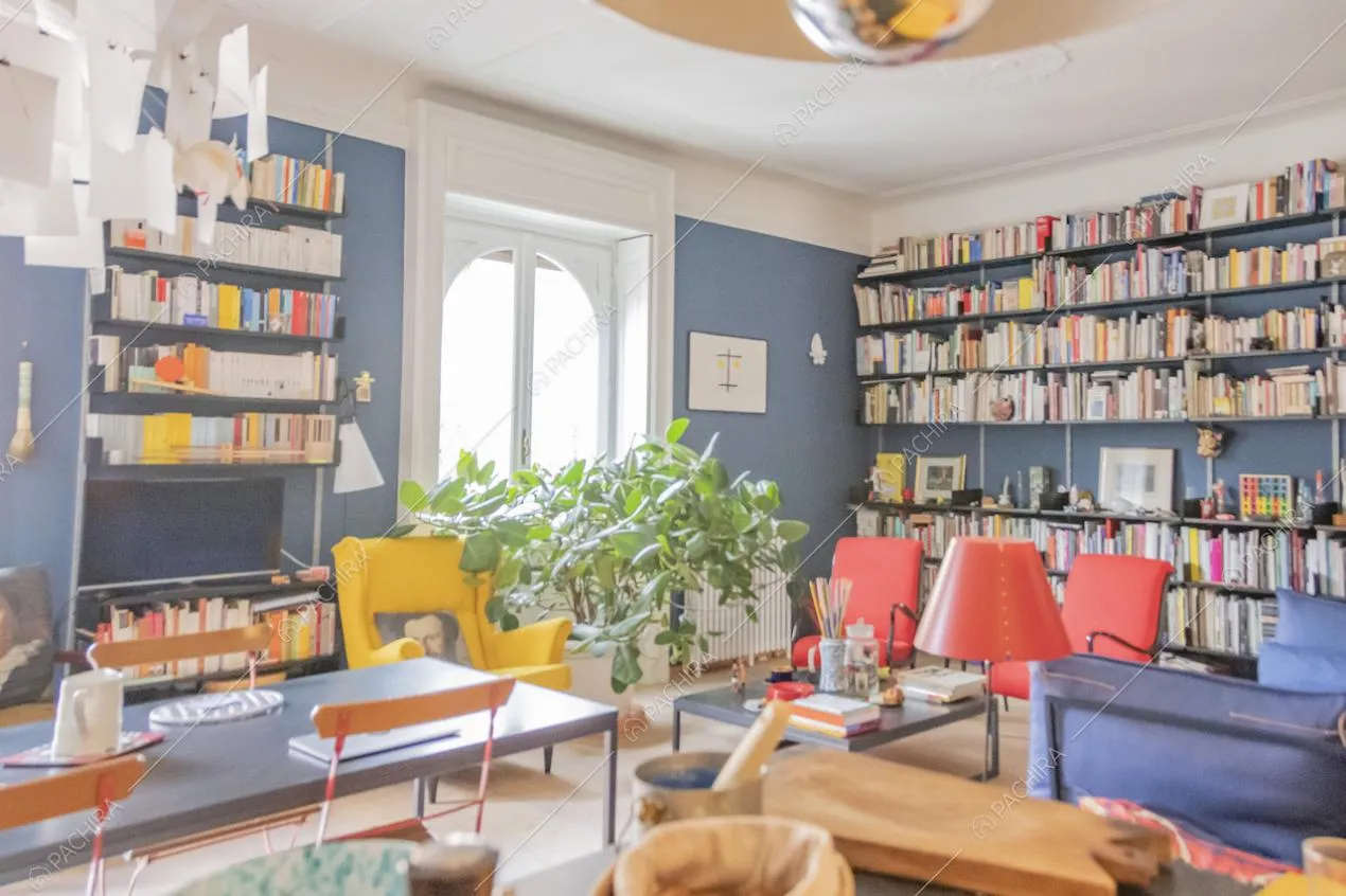 Poltrone gialle e rosse, librerie e porta finestra ad arco