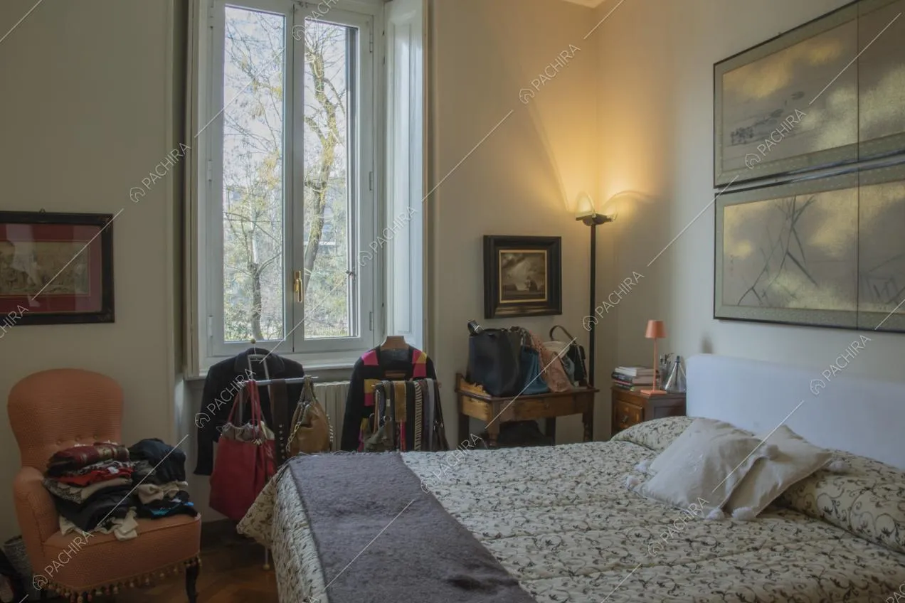 Letto matrimoniale, poltrona in pelle e quadri appesi alle pareti