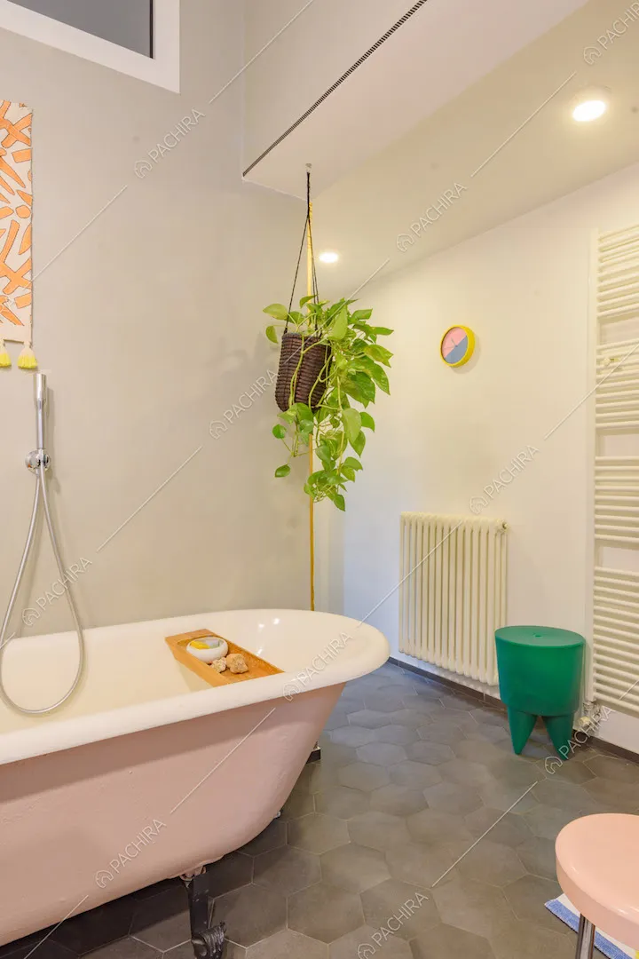 Vasca da bagno rosa, pavimento in cementine grigie e pareti bianche