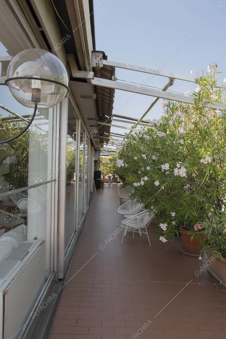 Terrazza con vetrate, piante e vista sullo skyline milanese