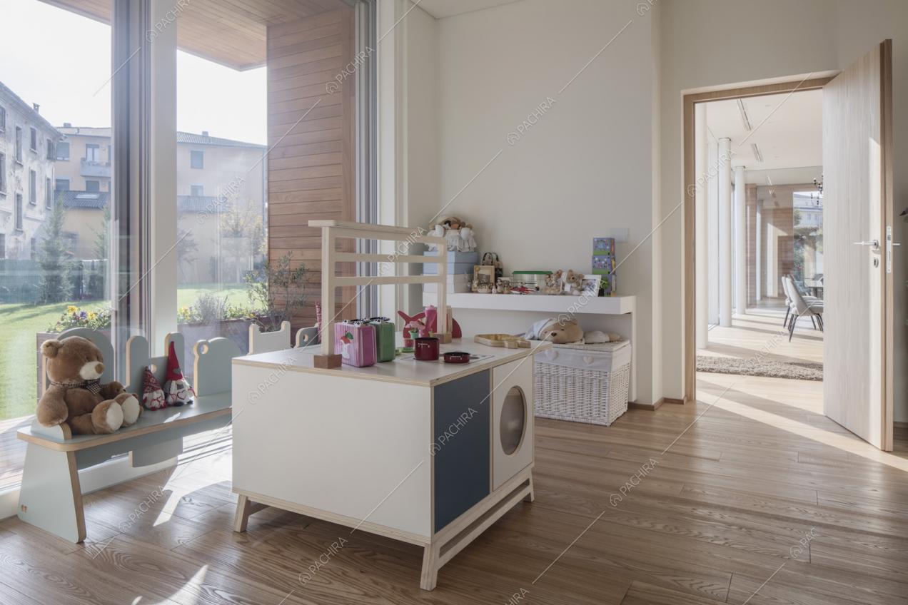Camera per bambini con giochi, pavimento in parquet, pareti bianche e vista sul soggiorno