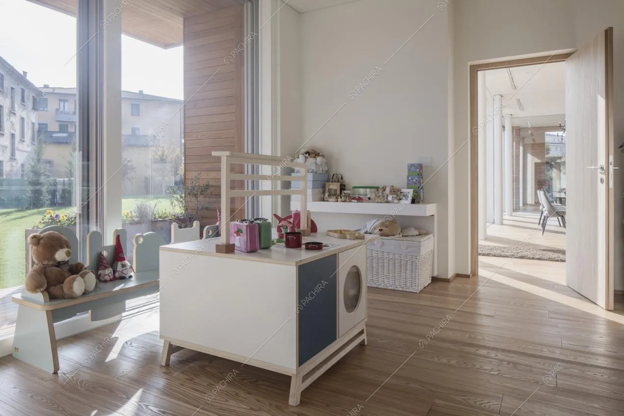 Camera per bambini con giochi, pavimento in parquet, pareti bianche e vista sul soggiorno
