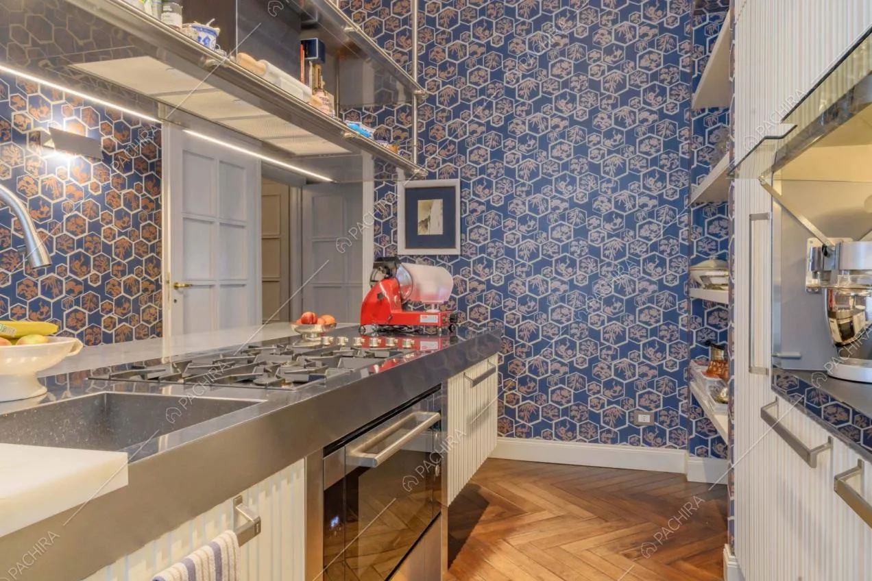 Cucina a isola con fornelli a gas, carta da parati e pavimento in parquet a spina di pesce