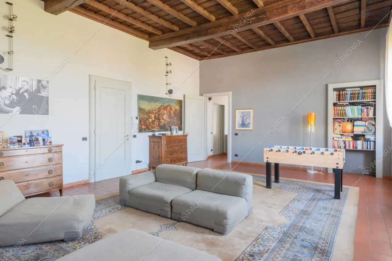Grande salotto con pouf, biliardino e soffitto a cassettoni in legno