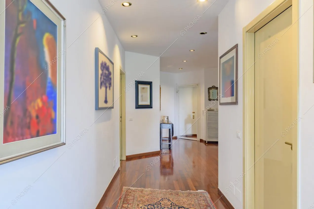 Corridoio con porta gialla, pareti bianche e pavimento in parquet