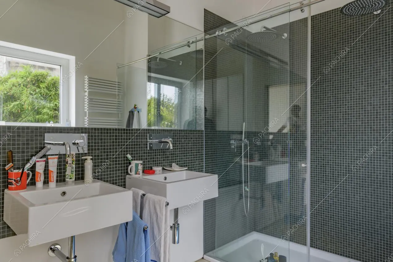 Doppio lavandino nel bagno con le pareti bianche e piccole piastrelle blu