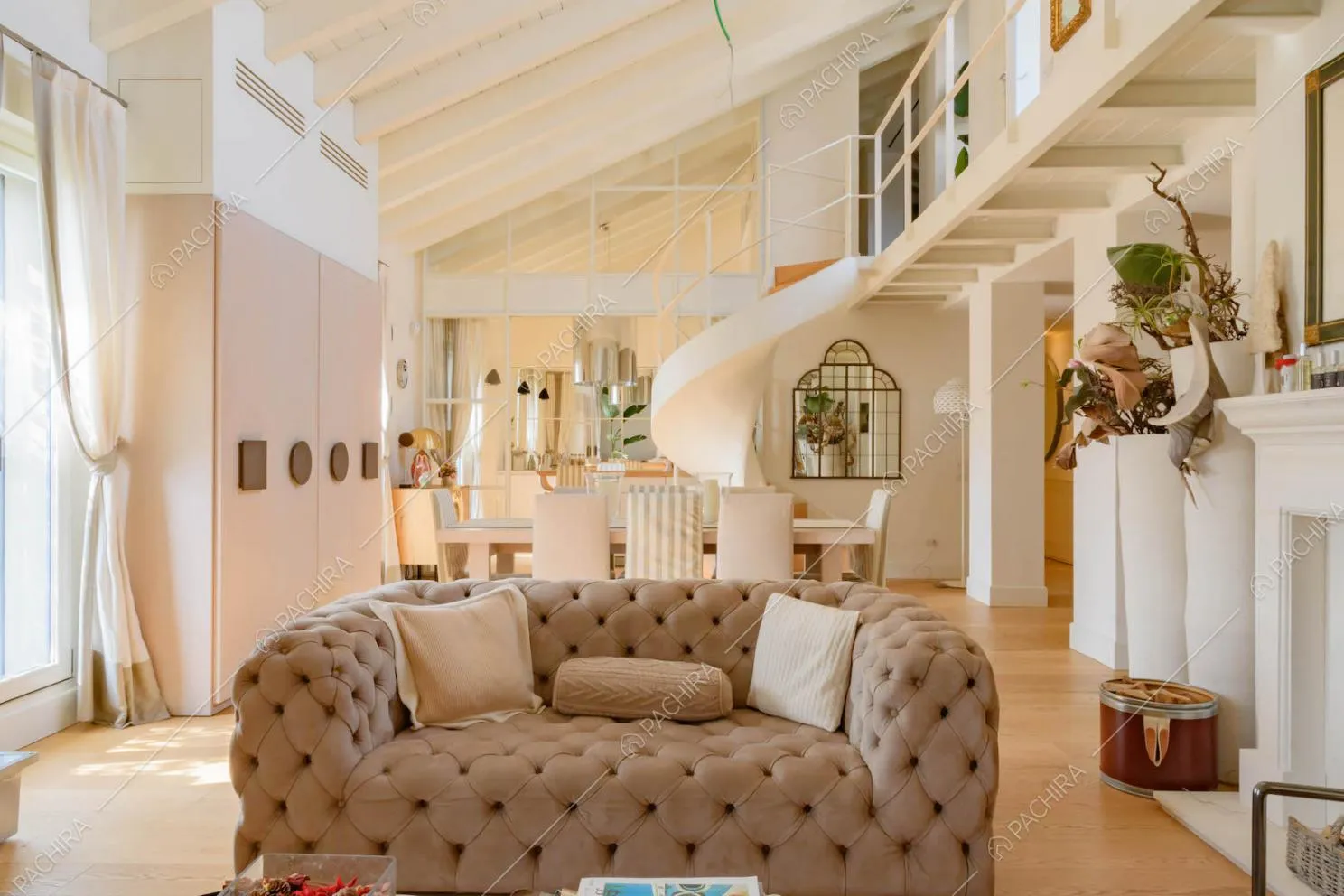 Divanetto marrone nella luminosa zona living con pavimento in parquet e scala a chiocciola
