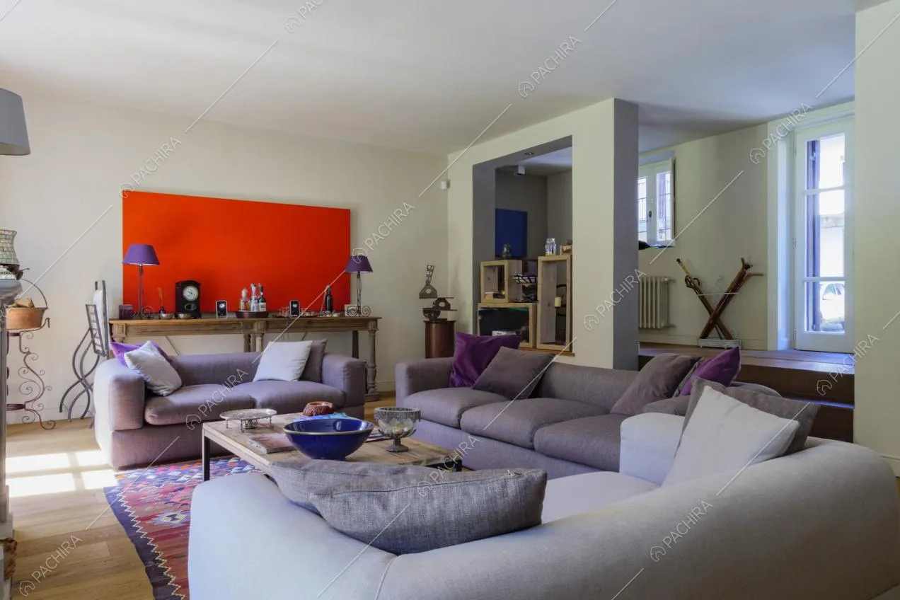 Salotto con pavimento in parquet, porta-finestra, divani viola e pareti bianche