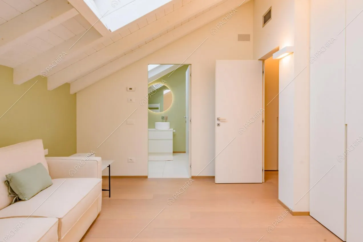 Sala con divano bianco, pavimento in parquet e soffitto con lucernario