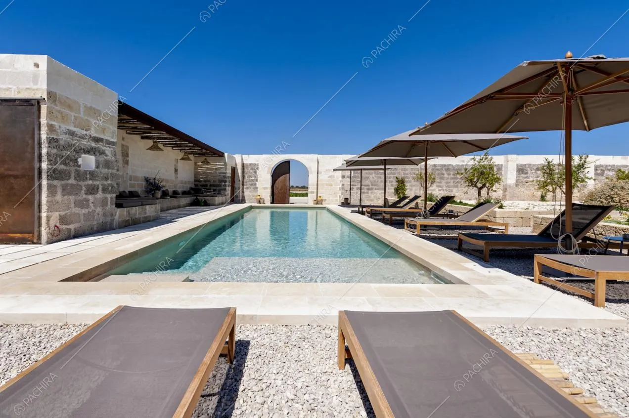 Bordo piscina con sdraio, ombrelloni e tavolini