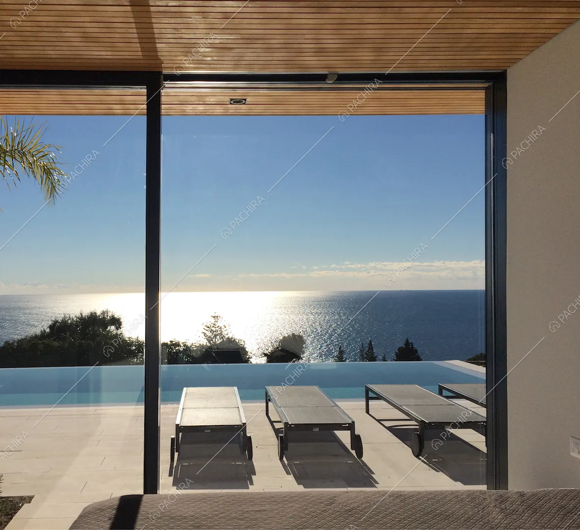 Dalla camera da letto matirmoniale, vista sulla terrazza con lettini e piscina a sfioro, e sul mare