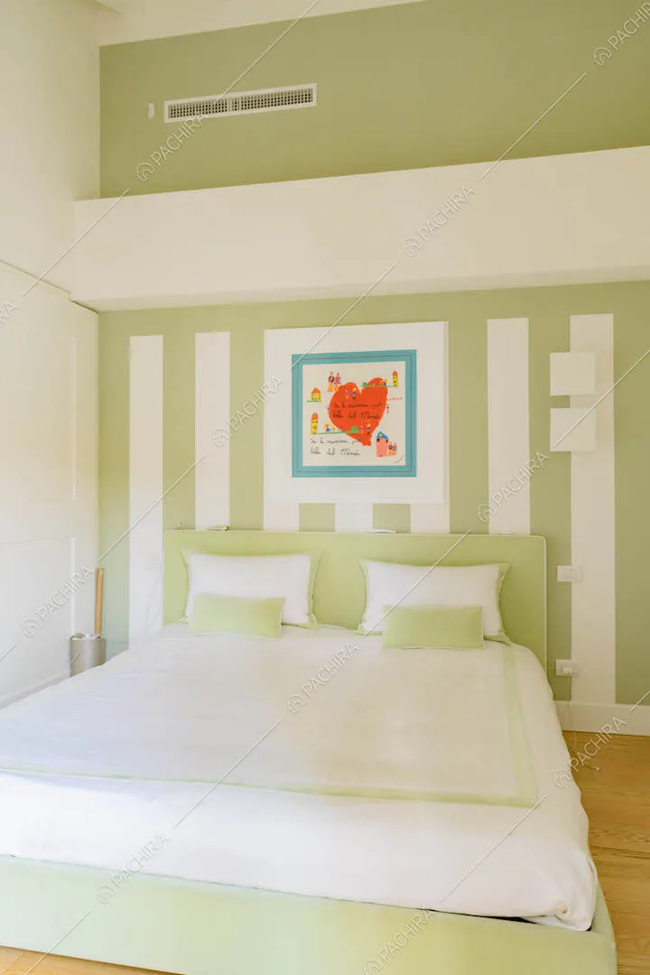Letto matrimoniale nella camera con pavimento in parquet e pareti bianche e verdi