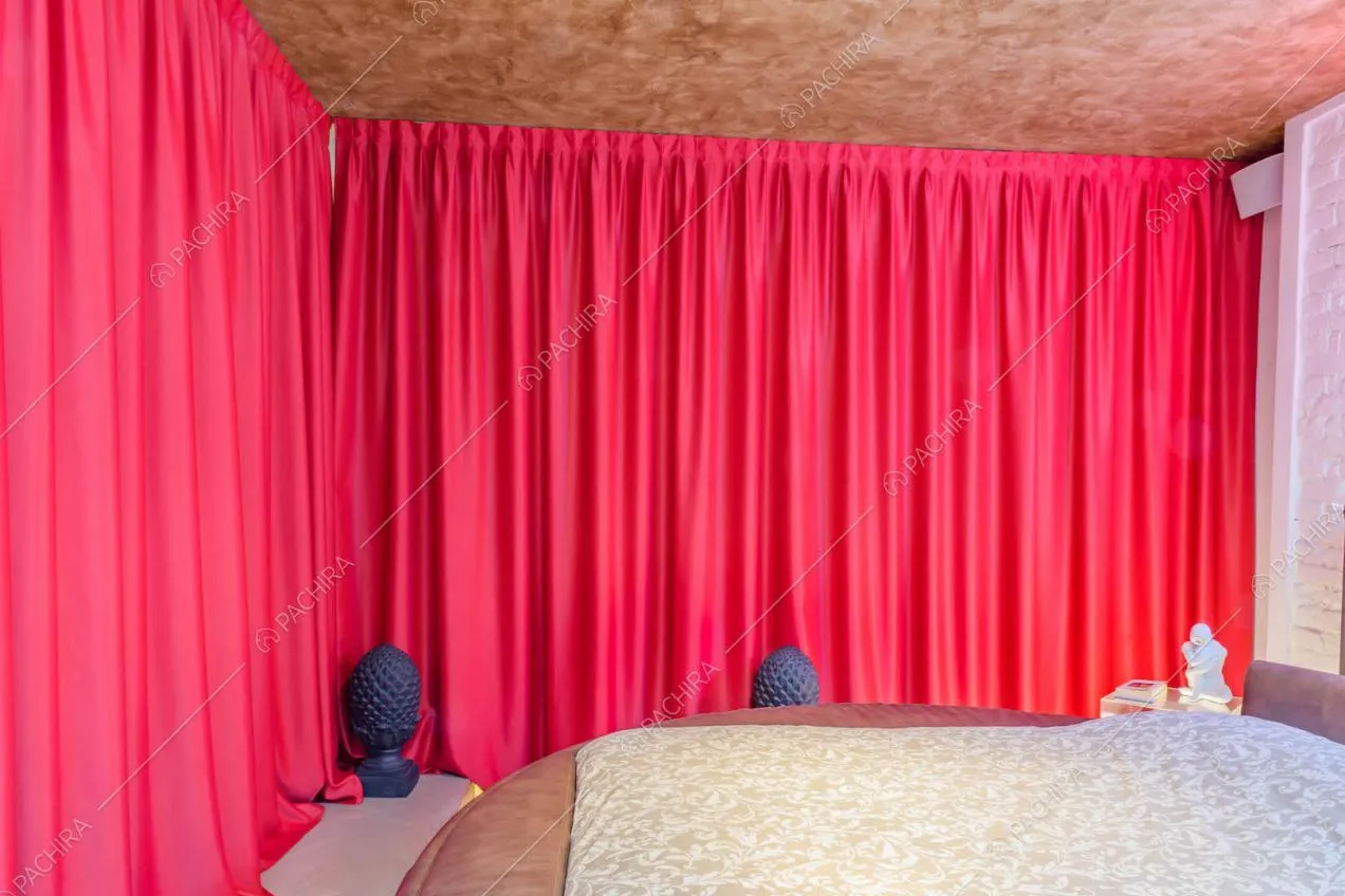 Tenda scorrevole fucsia nella camera con letto matrimoniale e parete in mattoni bianchi a vista