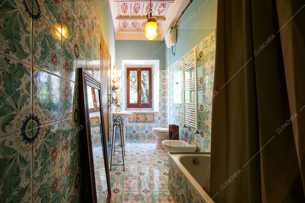 Bagno con vasca e pavimento e pareti in piastrelle dalla fantasia floreale