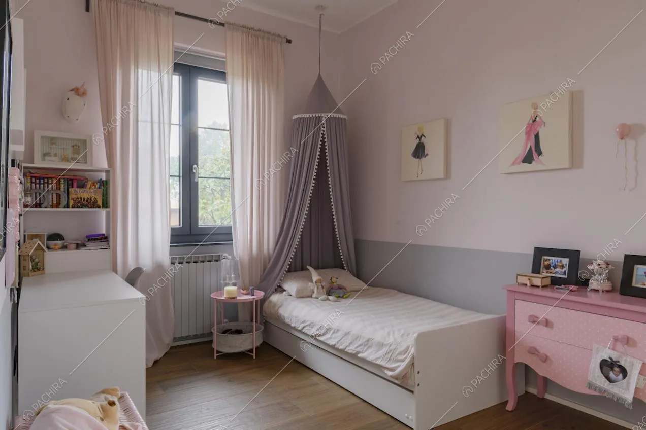 Letto singolo e mobile rosa con cassetti nella cameretta