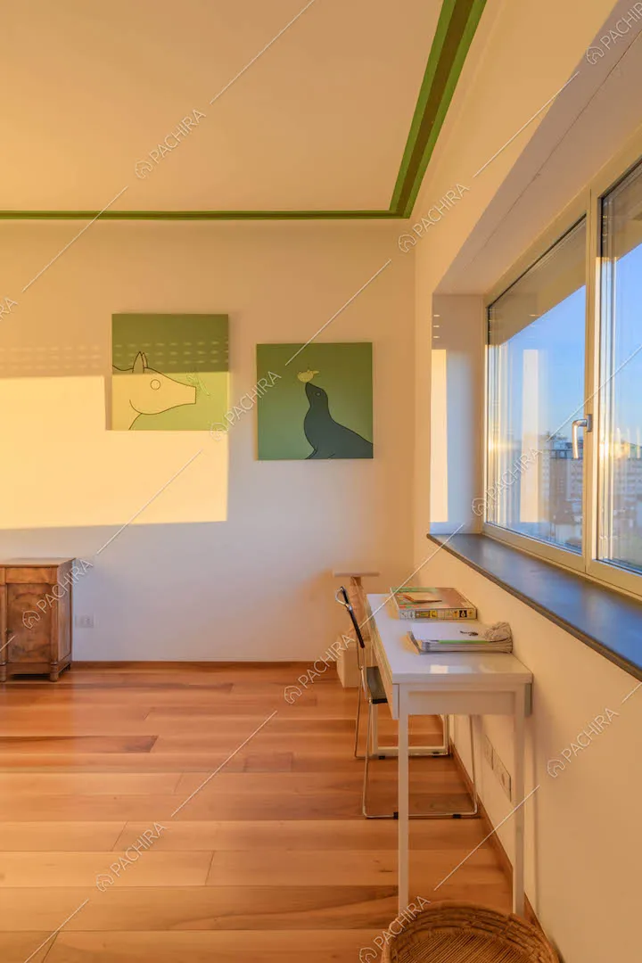 Pavimento in parquet, pareti bianche e finestre con vista sullo skyline milanese