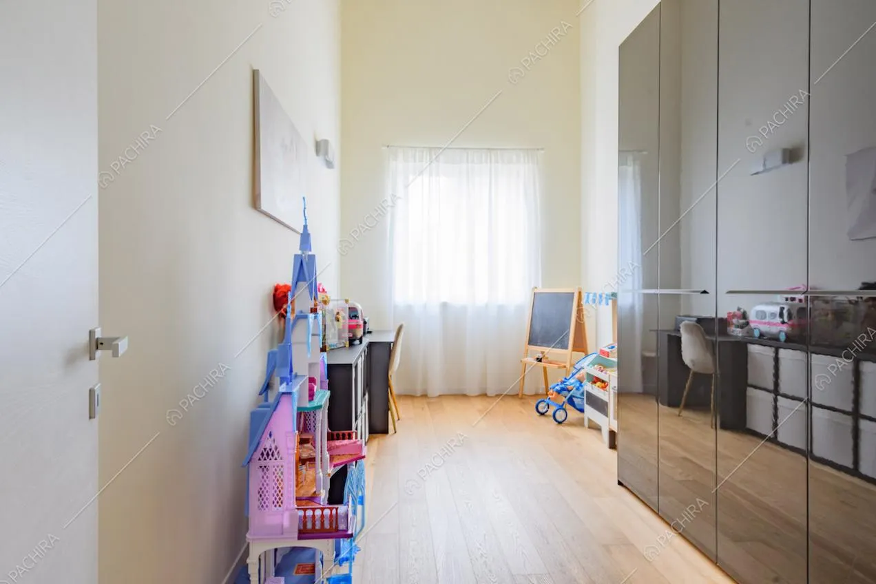 Camera con armadi neri, giochi, pavimento in parquet e pareti gialle