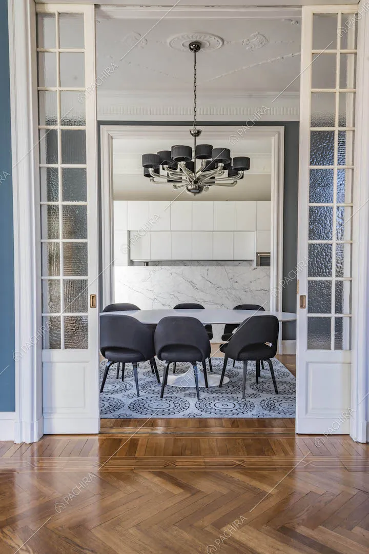 Vista sulla sala da pranzo con cucina a vista dal salotto con pavimento in parquet a spina di pesce