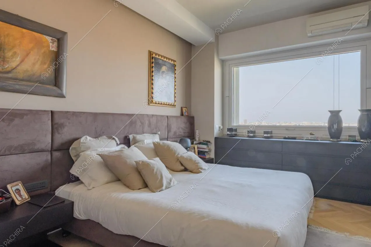 Letto matrimoniale nella camera con vetrate e pavimento in parquet a spina di pesce
