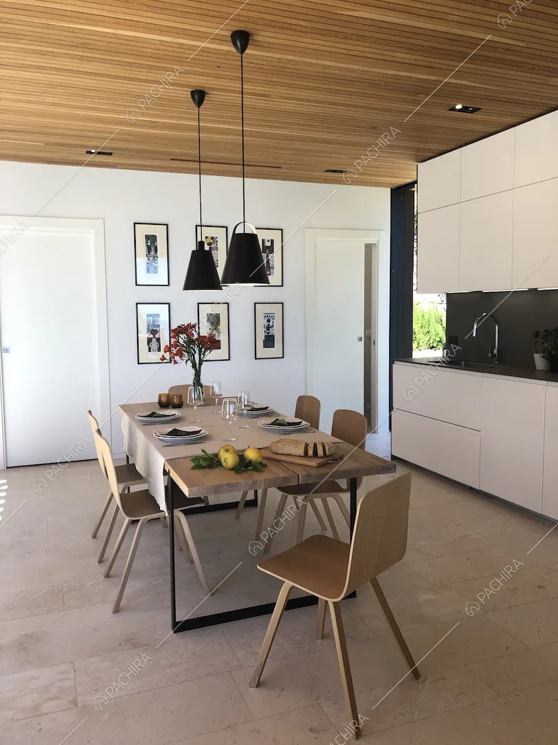 Tavolo da pranzo e cucina bianca a muro con fornelli a induzione e soffitto in legno