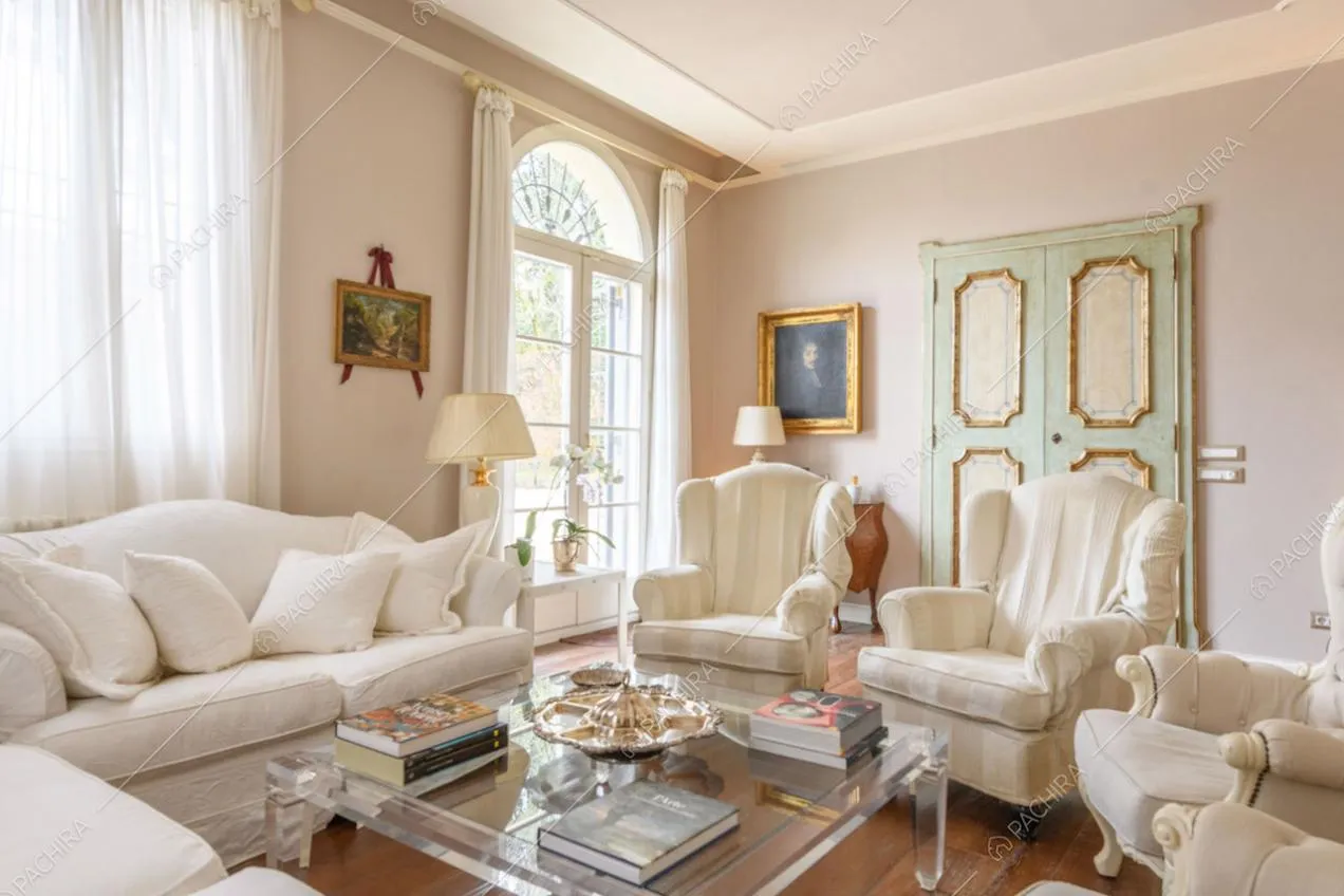 Salotto luminoso con boiserie sul soffitto, porta-finestra e pavimento in parquet