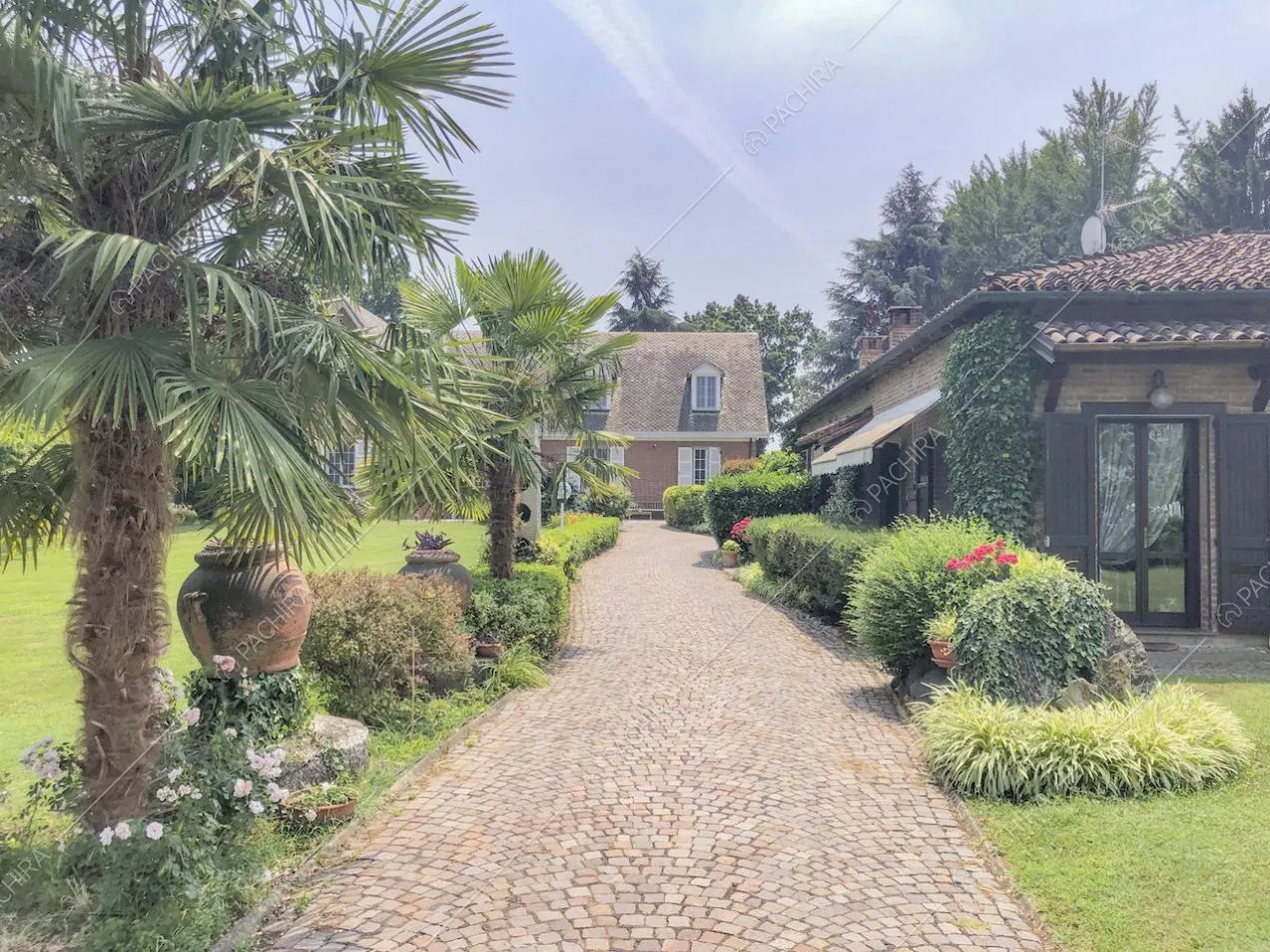 Dépendance nel giardino, palme e vialetto con mattoni