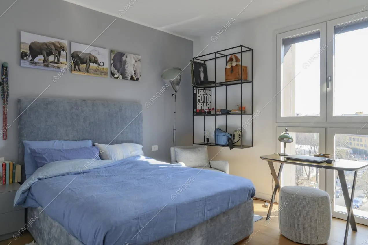Luminosa camera da letto matrimoniale dalle pareti bianche e grigie