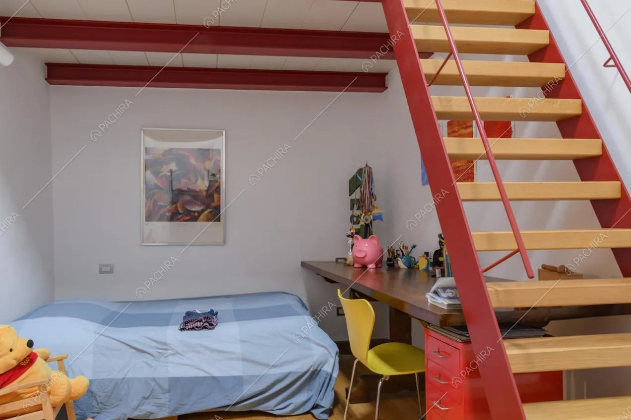 Camera da letto dalle pareti bianche con soppalco dagli infissi rossi