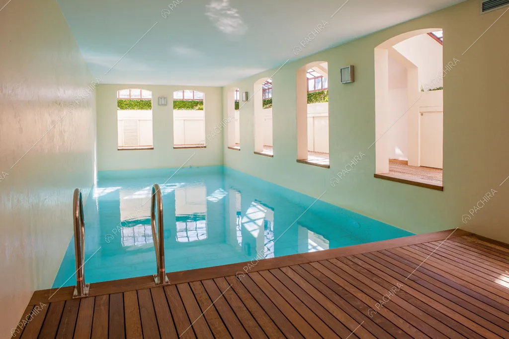 Grande piscina interna con pavimento in parquet e pareti bianche