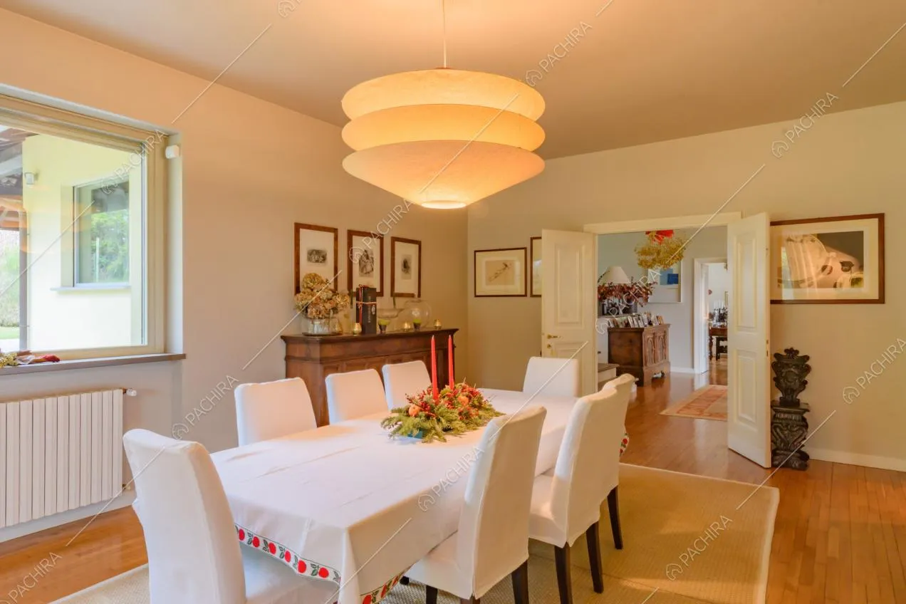 Tavolo da pranzo nella luminosa sala con pavimento in parquet e pareti bianche