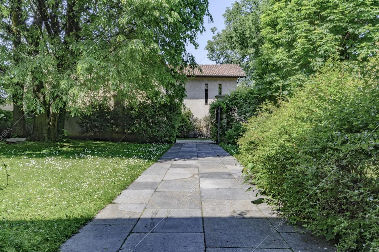 Vialetto in lastre di pietra della dimora storica immerso nel verde e scorcio sugli esterni
