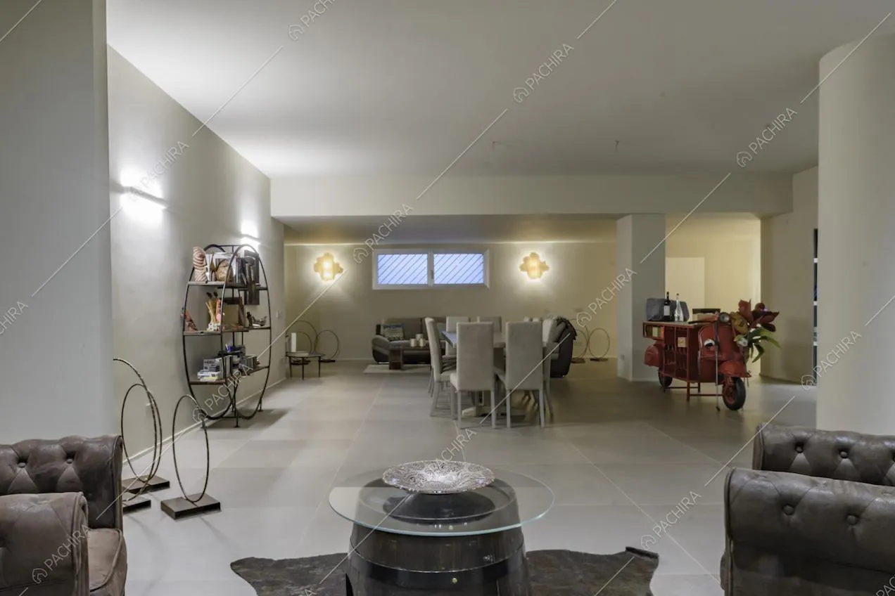 Spaziosa sala con divani e tavolino e, in fondo, tavolo da pranzo