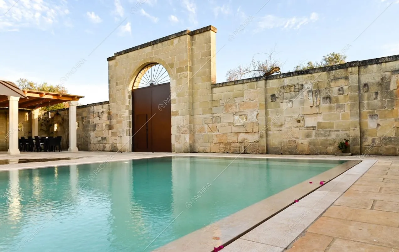 Mura di pietra che circondano la casa, con ampio portone, gazebo e piscina