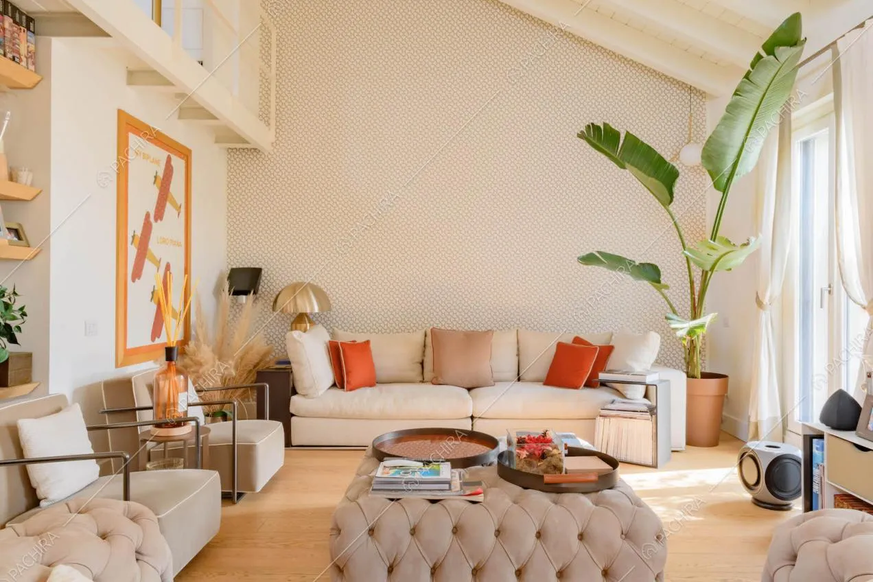 Divano e pouf beige nella zona living con pavimento in parquet e vetrate