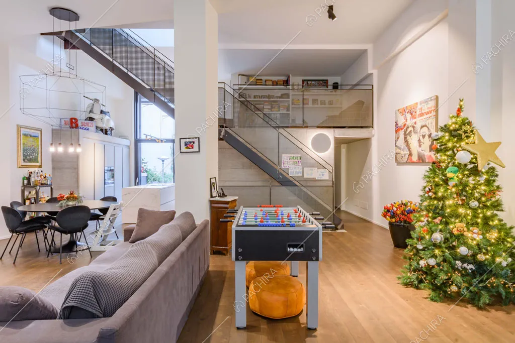 Zona living con pavimento in parquet, soppalco, pareti bianche e alti soffitti