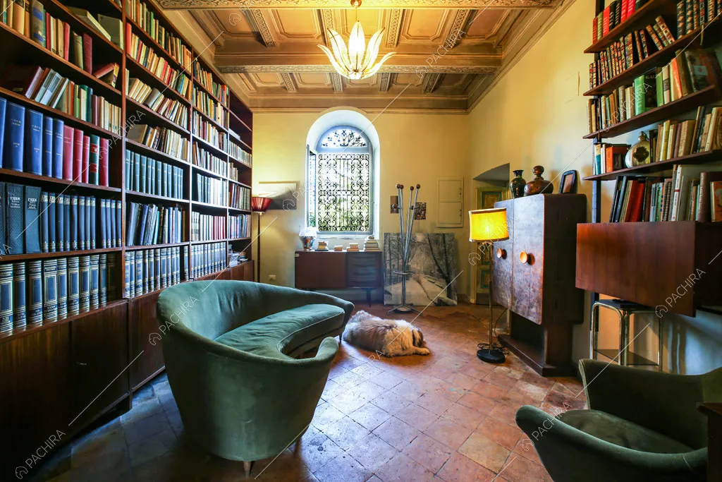 Biblioteca con librerie a parete, soffitto a cassettoni, scrivania e pavimento in cotto