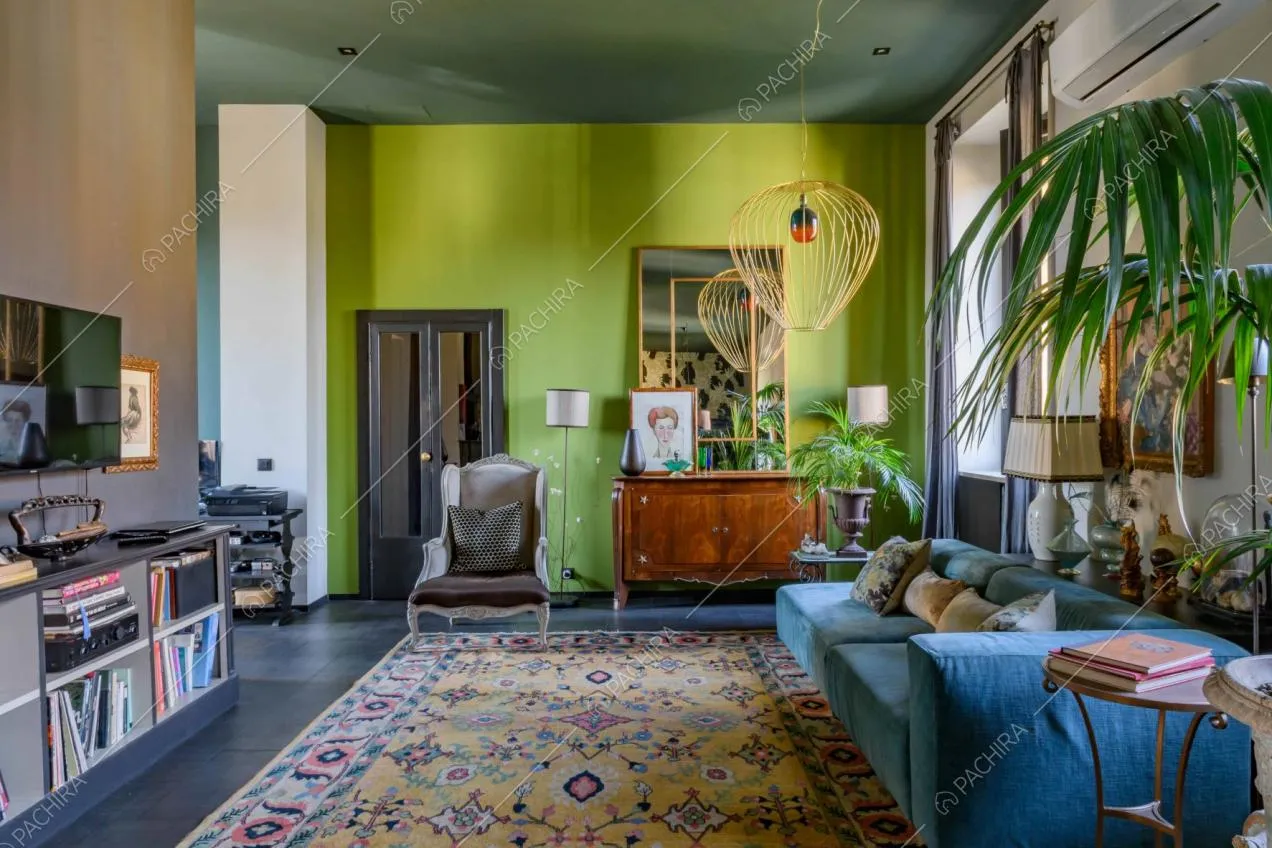 Sala con divano in velluto azzurro, ampio tappeto e pavimento nero in gres 