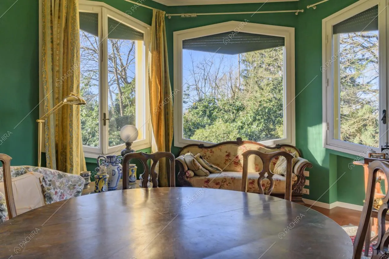 Tavolo da pranzo nel salotto dalle pareti verdi e dall'arredamento classico