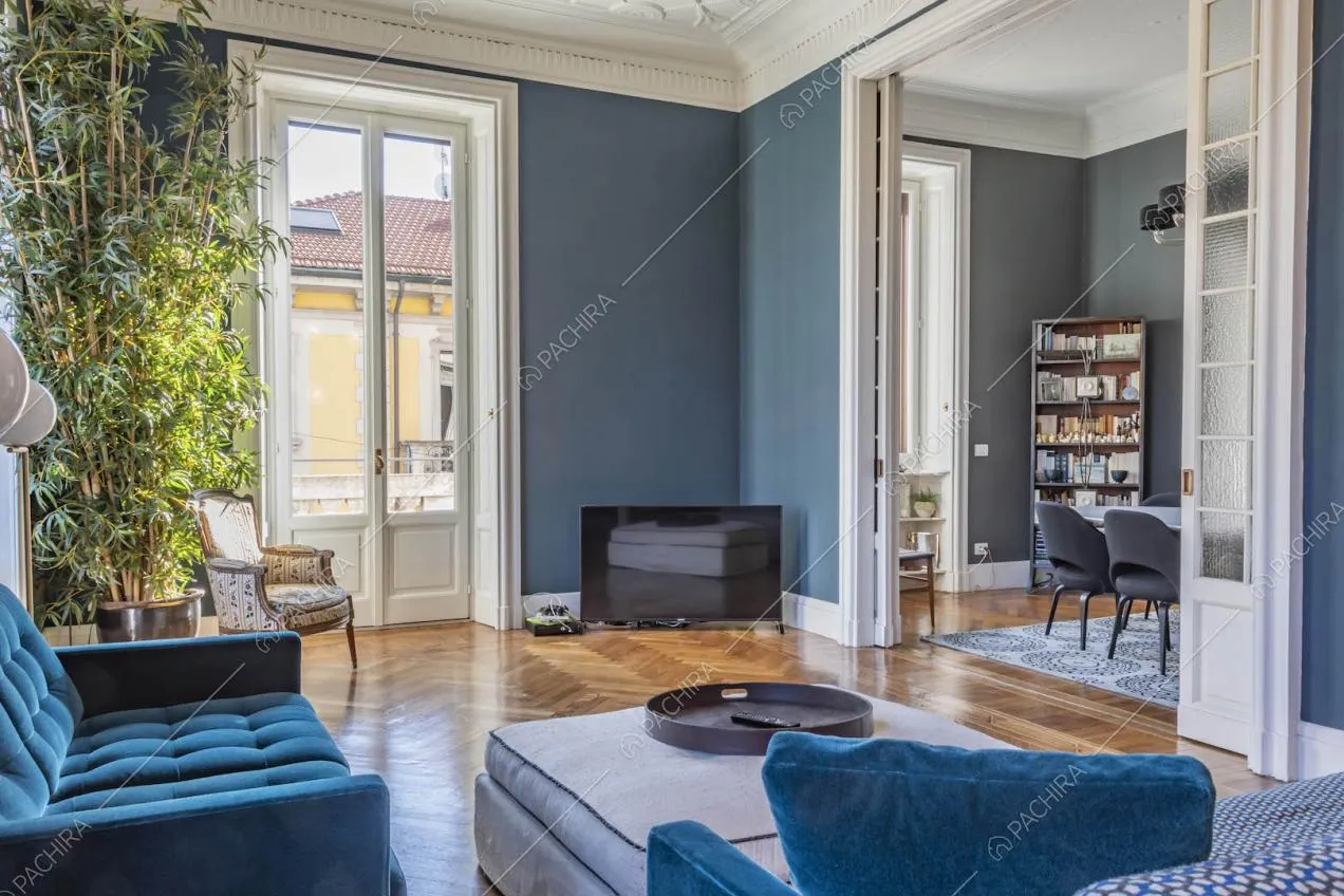 Dal salotto con pareti blu vista sulla sala da pranzo tramite porte a vetri scorrevoli