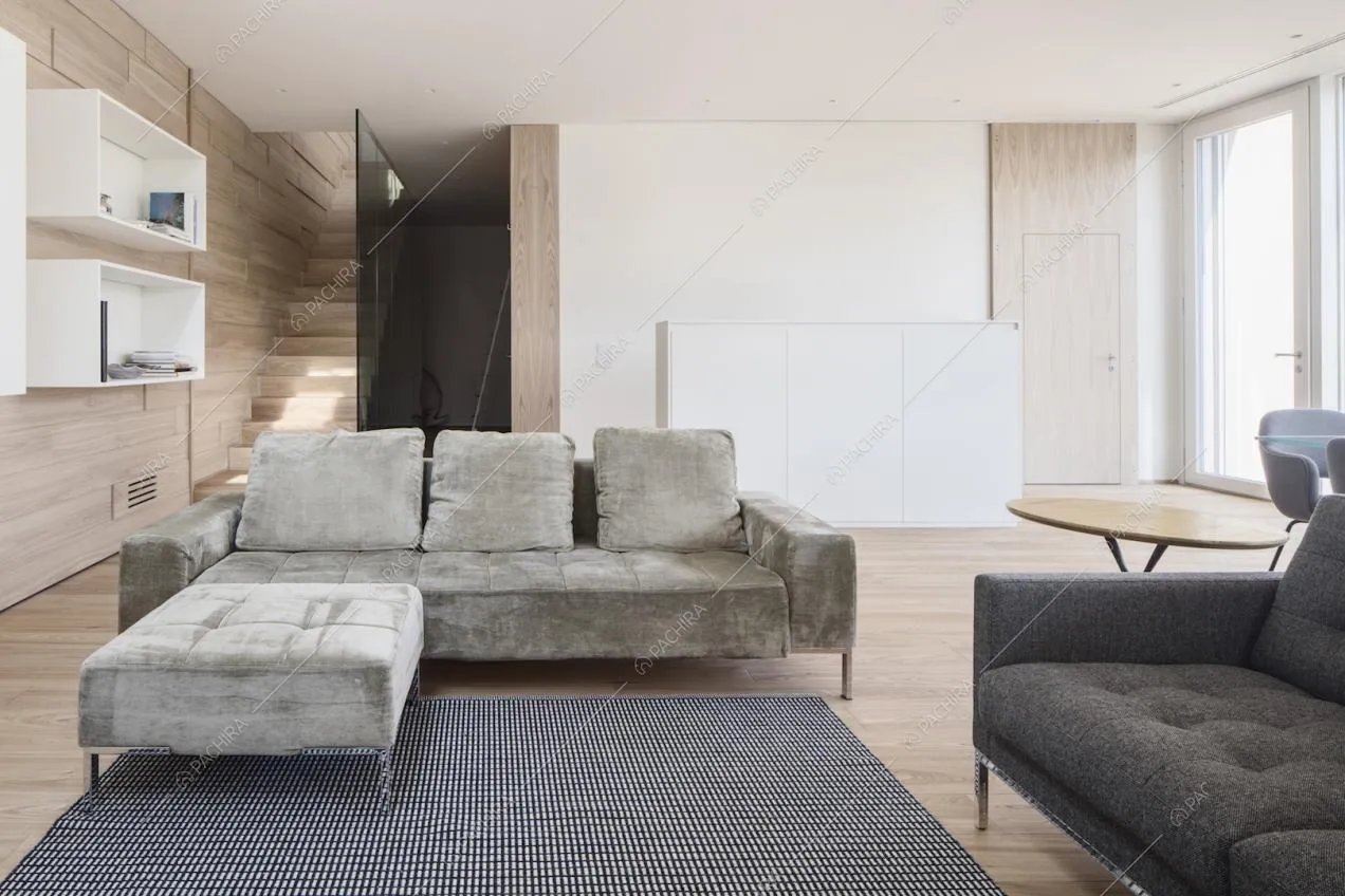 Divano angolare nel salotto dalle pareti in legno e dal pavimento in parquet illuminato di luce naturale grazie alle porte-finestre
