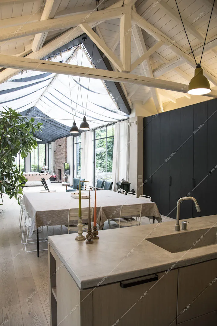 Zona pranzo con tavolo, cucina e lampade a sospensione