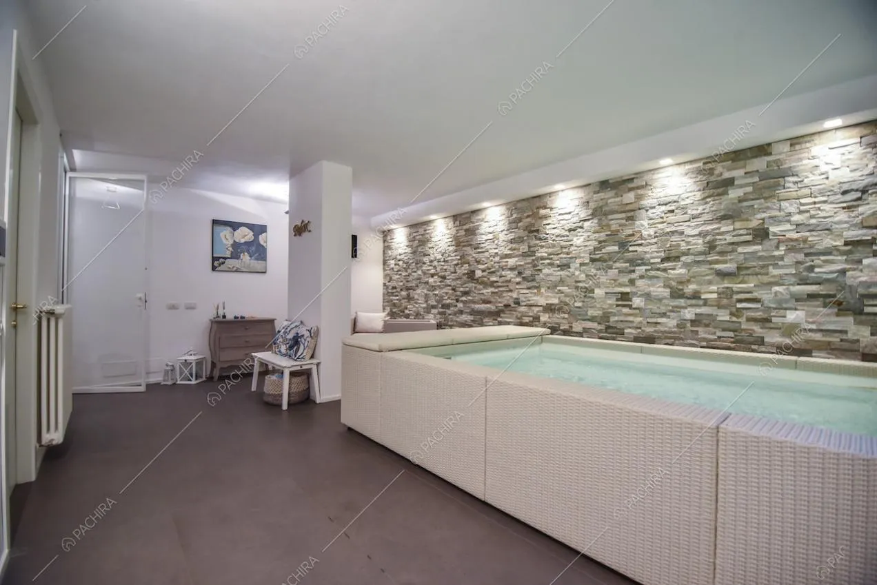 Grande vasca da bagno all'interno della villa e parete in pietra