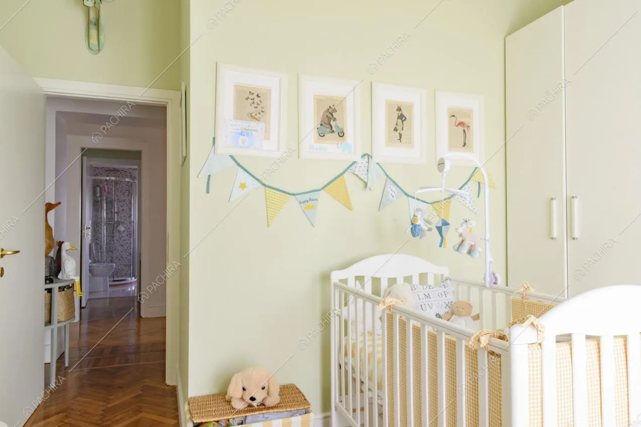 Camera dei bambini dalle pareti verdi, con culla e pavimento in parquet a spina di pesce